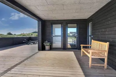 a wooden bench on a deck with a view of the ocean at 255-Harboore-Vejlby-Klit-37-A in Harboør
