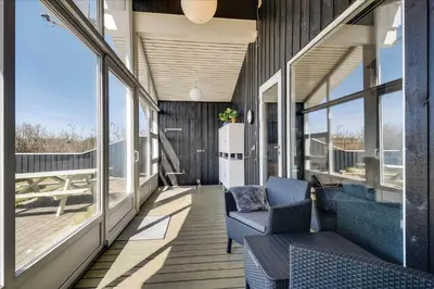 a balcony with two chairs and windows on a house at 100-Harboore-Vejlby-Klit-51 in Harboør