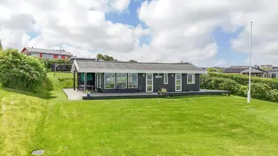 a small black house with a green yard at G230-Lemvig-Gyvelvej-30 in Lemvig