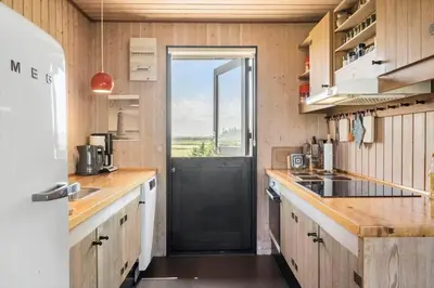 a kitchen with a black door and wooden cabinets at 218-Harboore-Dalevej-6-a in Harboør