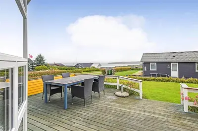 a wooden deck with a table and chairs on it at G131-Lemvig-Skovstjernevej-31 in Lemvig