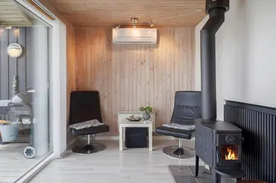 a living room with two chairs and a stove at 119-Harboore-Neerlandiavej-32 in Harboør
