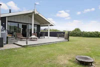 a patio with two benches and a table in a yard at 119-Harboore-Neerlandiavej-32 in Harboør