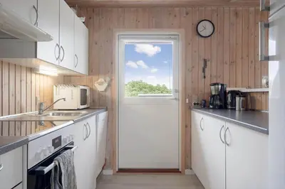 a kitchen with a door and a clock on the wall at 119-Harboore-Neerlandiavej-32 in Harboør
