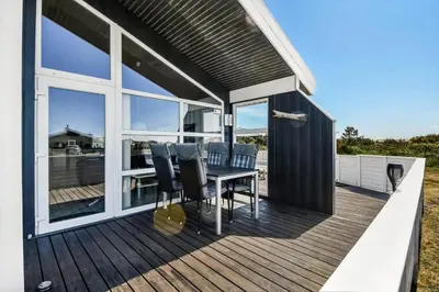 a wooden deck with a table and chairs on it at 102-Harboore-Vejlby-Klit-21 in Harboør