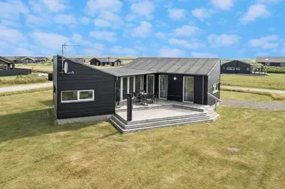 a black tiny house on a grass field at 227-Harboore-Bjergehusvej-4 in Harboør