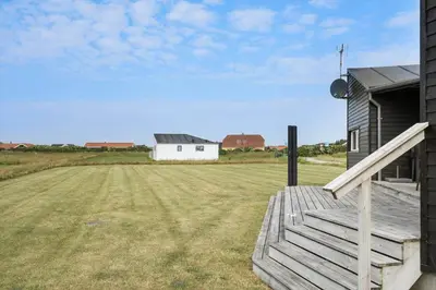 a house with a wooden porch and a field at 227-Harboore-Bjergehusvej-4 in Harboør