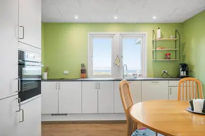 a kitchen with white cabinets and a table and a window at G147-Lemvig-Syrenvej-47 in Lemvig