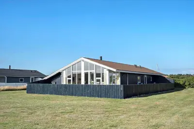 a large house with glass windows on a field at 801-Harboore-Vejlby-Klit-89 in Harboør