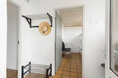 a hallway with a chair and a hat on the wall at 803-Harboore-Merchantvej-9-A in Harboør
