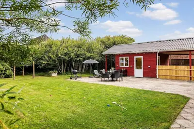 a red barn with a table and chairs in a yard at 727-Thyboron-Magevej-10 in Thyborøn