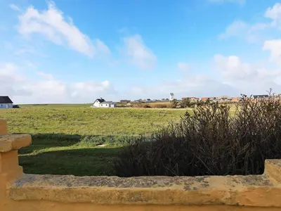a field of grass with a house in the distance at 12 person holiday home in Lemvig in Lemvig
