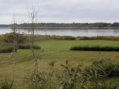 a field of grass next to a body of water at 6 person holiday home in Hurup Thy-By Traum in Sindrup