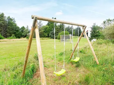two swings in a field with a soccer ball at 7 person holiday home in Fjerritslev-By Traum in Fjerritslev