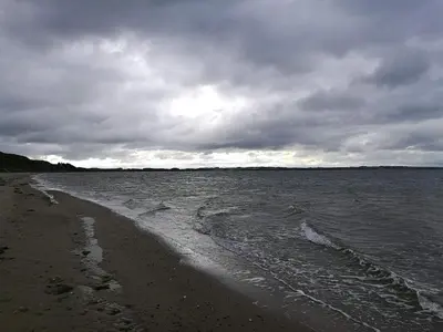 a beach with a cloudy sky and the water at 6 person holiday home in Struer-By Traum in Struer