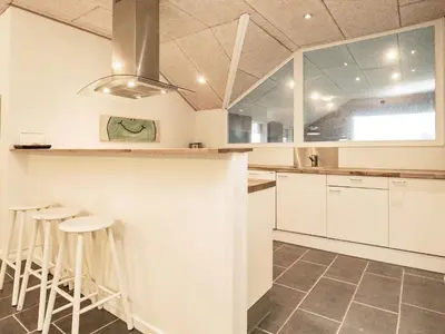 a kitchen with white cabinets and bar stools at Holiday home for 24 guests, Brovst in Brovst
