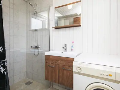 a bathroom with a shower and a sink and a washing machine at 6 person holiday home in Løkken in Løkken