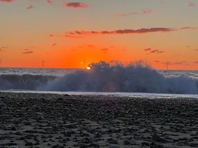 a wave breaking on a beach at sunset at 6 person holiday home in Harboøre-By Traum in Harboør