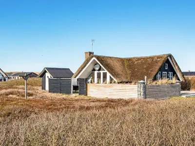a house with a thatched roof on the beach at 6 person holiday home in Harboøre-By Traum in Harboør