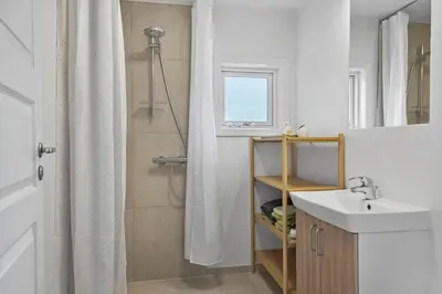 a bathroom with a sink and a shower with a shower curtain at 813-Harboore-Neerlandiavej-136 in Harboør