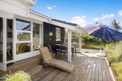 a wooden deck with a table and an umbrella at BL1113-Saltum-Revlingevej-26 in Saltum