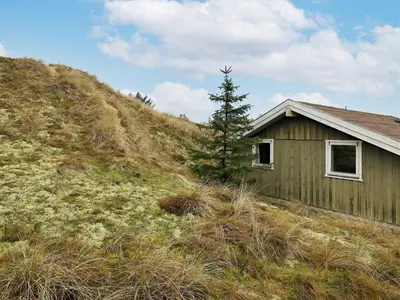 a house on a hill with a tree next to it at Spacious Retreat with Views - By Traum Ferienwohnungen in Blokhus