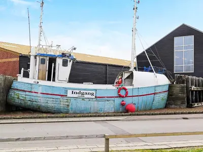 an old blue boat sitting next to a building at 5 person holiday home in Thyborøn in Thyborøn