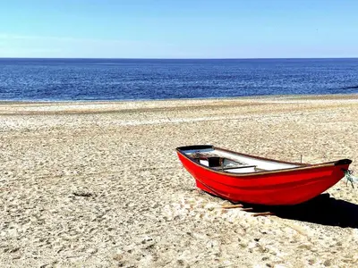 a red boat sitting on a beach next to the ocean at 6 person holiday home in Lemvig in Lemvig