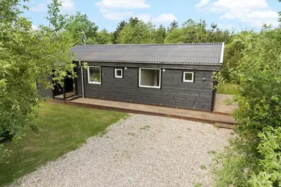 a black house with a wooden deck in a yard at LF10320-Hurup-Thy-Nattergalevej-2-B in Sønder Ydby