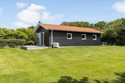 a black house with an orange roof on a grass field at LF101-Vestervig-Hellesvej-1 in Vestervig