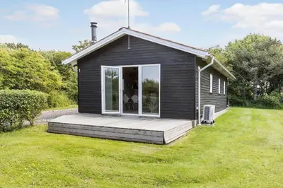 a small black house with a wooden porch at LF101-Vestervig-Hellesvej-1 in Vestervig