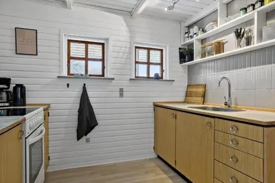 a kitchen with white walls and wooden cabinets and a sink at LF14163-Roslev-Kybehuse-3 in Roslev