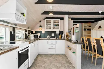 a kitchen with white cabinets and tables and chairs at LF12017-Spottrup-Albaekparken-144 in Spottrup