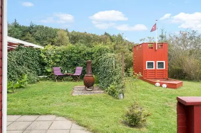 a garden with a red house and purple chairs at LF11171-Struer-Klintevej-14 in Struer