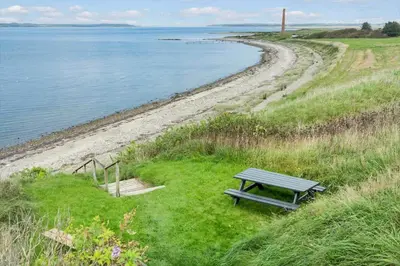 a bench sitting on the grass next to a beach at LF14137-Spottrup-Fjordvej-39 in Spottrup