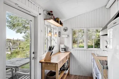 a kitchen with white walls and a table and windows at LF11974-Struer-Havstokken-15A in Struer