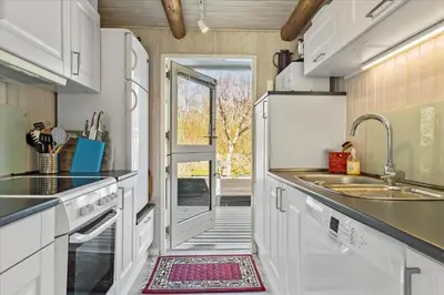 a kitchen with white cabinets and a door leading to a patio at LF14223-Roslev-Livovej-9 in Roslev