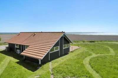 a small house with a red roof in a field at LF10209-Thyholm-Markvejen-9 in Thyholm