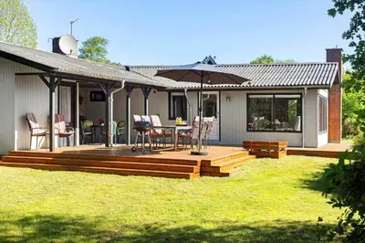 a house with a wooden deck with an umbrella at LF14102-Roslev-Eskovvej-102 in Roslev