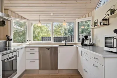 a kitchen with white cabinets and stainless steel appliances at LF10210-Thyholm-Skovstien-10 in Thyholm