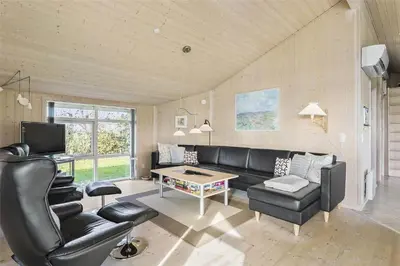 a living room with a black leather couch and a table at LF884-Snedsted-Kongens-Borer-2 in Snedsted