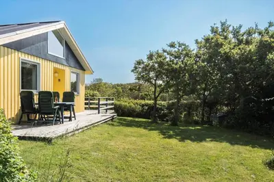 a yellow house with a table and chairs on a deck at LF11111-Struer-Granvej-11 in Struer