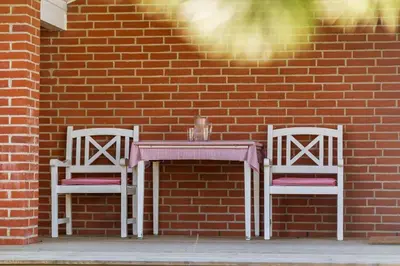 two chairs and a table in front of a brick wall at LF10229-Thyholm-Skovstjernevej-9 in Thyholm