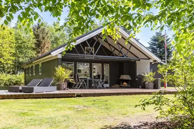 a green house with a patio and a fireplace at LF15124-Hojslev-Jelsevej-124 in Højslev