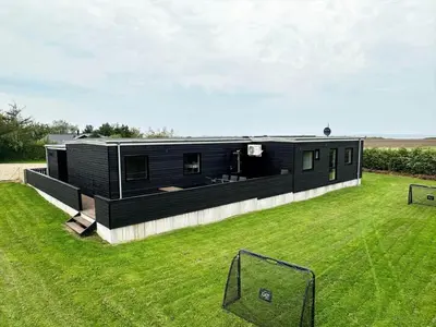 a black house in a field with a grass yard at LF12086-Vinderup-Vigen-86 in Vinderup