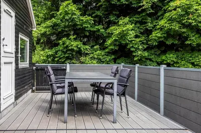 a table and chairs on a deck with a fence at LF0027-Thyholm-Sondbjerg-Strandvej-27 in Thyholm