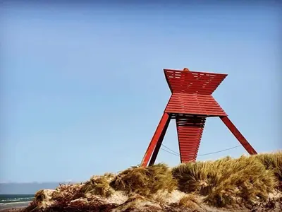 a red wooden structure on a sandy beach at 6 person holiday home in Blokhus