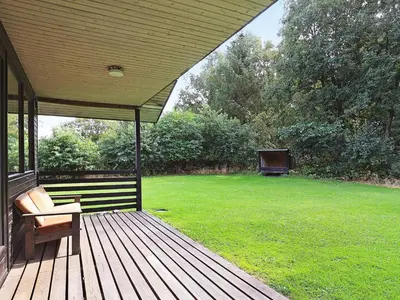 a wooden porch with a bench and a field of grass at 6 person holiday home in Øster Assels in Øster Assels
