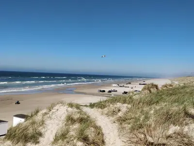 a beach with cars parked on the sand and the ocean at Welcoming 6 person holiday home in Blokhus in Blokhus