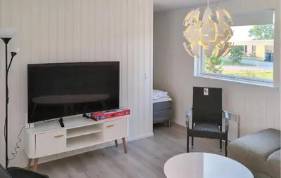 a living room with a flat screen tv and a chair at 3 Bedroom Nice Home In Løgstrup in Løgstrup